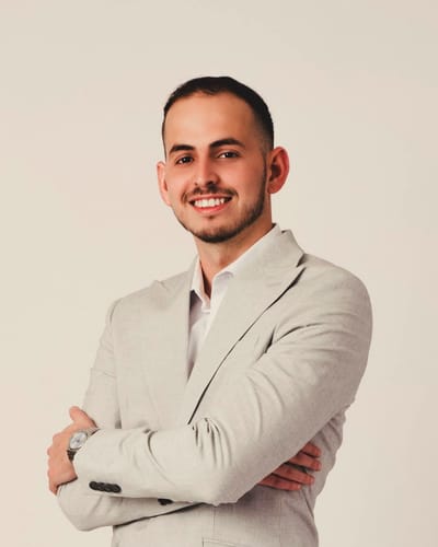 Portrait of Rafael Gomez in a light grey blazer, arms crossed